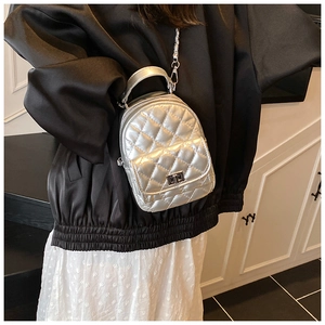 Detail einer silbernen gesteppten Mini-Rucksacktasche mit Metallkette und Drehverschluss