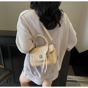 Detail view of beige oil wax leather crossbody bag with silk scarf and silver twist lock