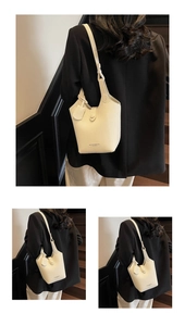 Detailed view of the creamy white lychee grain leather bucket bag on model's shoulder