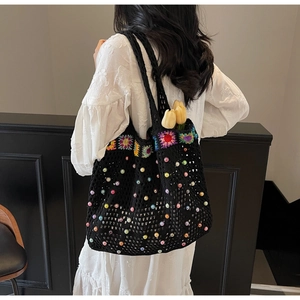 Detail of bohemian black knit tote bag with colorful crochet flowers and bead decorations