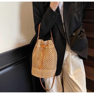 Detail of hollow woven straw bucket bag with brown leather drawstring and shoulder strap