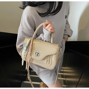 Detail of beige faux leather handbag with silver lock and decorative plaid scarf