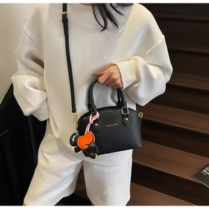 Close-up of black litchi grain bucket bag with gold lettering and cute elephant charm