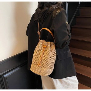 Close-up of hollow woven bucket bag featuring straw texture and drawstring leather strap