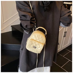 Detail der cremefarbenen Stepptasche mit silbernem Drehverschluss und Metallkettenriemen