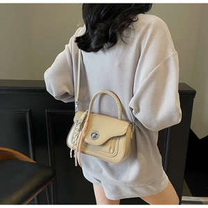 Detail of beige faux leather square bag with silver twist lock and colorful silk tassel