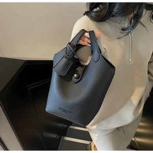 Detailed close-up of a black lychee texture leather bucket bag with snap button closure