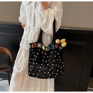 Detail of black crochet tote bag featuring colorful sunflower accents and bead embellishments