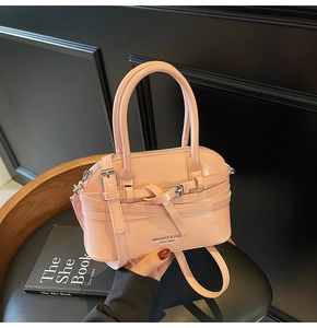 Detail of light pink glossy leather shell bag featuring silver metal buckle and strap