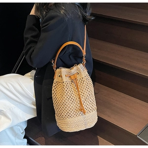 Close-up of woven hollow bucket bag with brown leather drawstring and handle details