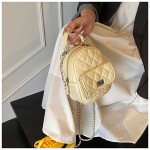 Detail eines cremefarbenen gesteppten Mini-Rucksacks mit glänzendem Leder und Metalldrehverschluss