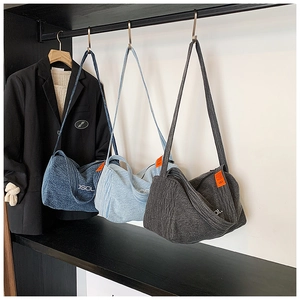 Tre borse tote minimaliste in denim blu e grigio appese a un supporto in metallo nero