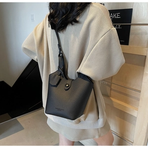 Chic black litchi pattern bucket bag styled with a beige sweater for casual daily wear