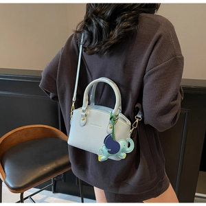 Detail of light blue lychee pattern bucket bag with elephant charm and gold hardware