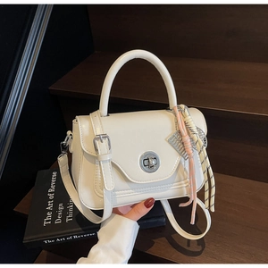 Detail of cream vintage oil wax leather handbag with metal buckle and silk ribbon