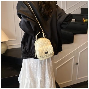 Eleganter beiger Mini-Rucksack mit klassischer Steppung und edlen Kettenriemen im Detail