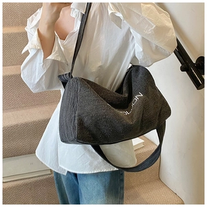 Dettaglio della borsa tote in denim grigio scuro con scritta OLDON indossata dal modello