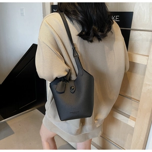Detail view of the black lychee pattern leather bucket bag on a model's shoulder