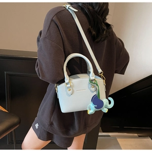 Close-up of light blue pebbled leather bucket bag featuring cute elephant charm detail