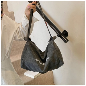 Dettaglio borsa tote in denim grigio scuro con stampa di lettere bianche sul lato