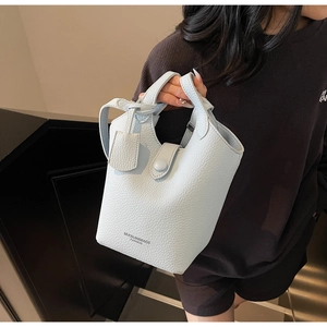 Detailed view of light blue lychee pattern bucket bag with single handle and snap closure