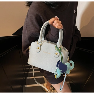 Close-up of light blue lychee pattern leather bucket bag with golden hardware and elephant charm
