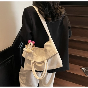 Detalle de bolso tote de cuero granulado blanco con un colgante de peluche de cachorro
