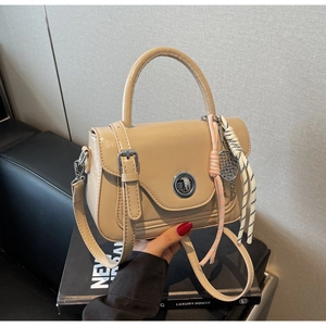 Close-up of beige oil wax leather handbag with silver twist lock and woven rope charm