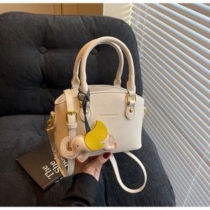 Detail of cream leather bucket bag featuring pebbled texture and elephant charm