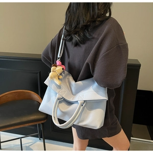 Detalle del bolso tote azul claro con patrón de lichi, colgante de perro y correa extraíble