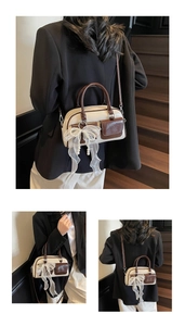 Detail of cream and dark brown Boston bag featuring a pearl mesh bow charm on leather handle