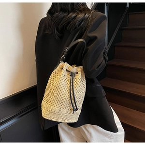 Straw bucket bag with black leather drawstring and strap shown on a model