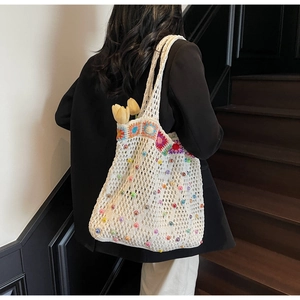 Detailed knit texture of crochet tote bag with colorful beads and floral patterns