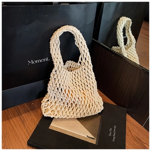 Gros plan détaillé d'un sac à main en macramé beige posé sur une surface en bois naturel