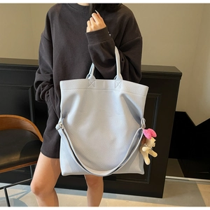 Detalle del bolso tote de piel granulada azul claro con un tierno colgante de perrito