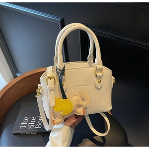 Close-up of white pebble leather bucket bag with gold hardware and elephant charm