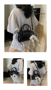 Detail view of black patent leather Boston bag with white lace pearl bow and side pocket
