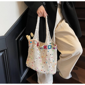 Detail of hand-knitted tote bag with floral embroidery and colorful beads in use