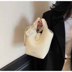 Detail of cream lychee texture leather bucket bag featuring MUONJIN brand lettering