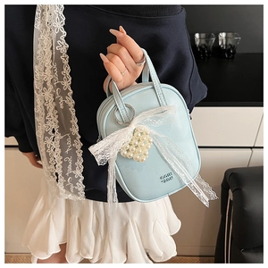 Dettaglio mini borsa azzurra con fiocco in pizzo bianco e ciondolo di perle elegante