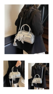 Detail of silver metallic Boston bag featuring white organza bow and pearl pendant charm