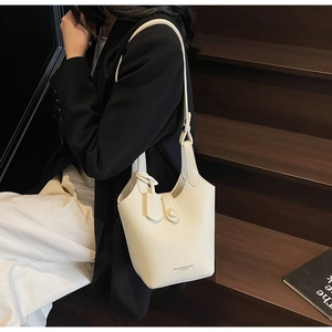 Detailed macro view of the cream lychee grain leather texture and brand logo on the bucket bag