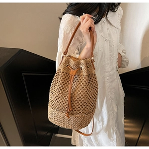 Detail of woven straw bucket bag featuring brown leather drawstring and mesh texture