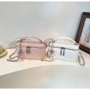 Detail of pink and white quilted crossbody bags with golden ball chain and top handle