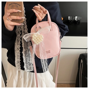 Dettaglio della borsa in pelle rosa con fiocco in pizzo e ciondolo a cuore di perle