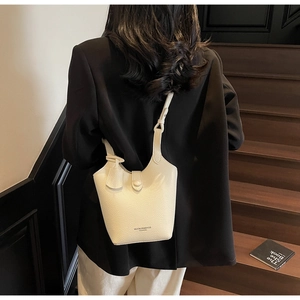 Close-up of creamy white lychee grain leather bucket bag with metallic buckles