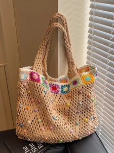 Beige crochet tote bag with colorful sunflower border and bead accents in sunlight