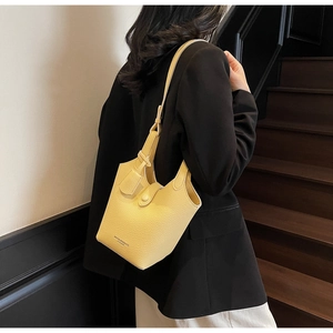 Detail of a bright yellow litchi pattern bucket bag with a magnetic buckle closure