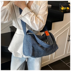 Dettaglio macro della borsa tote in denim blu con etichetta arancione e ricamo