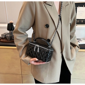 Close-up of a black quilted leather box bag with silver chain strap on a model